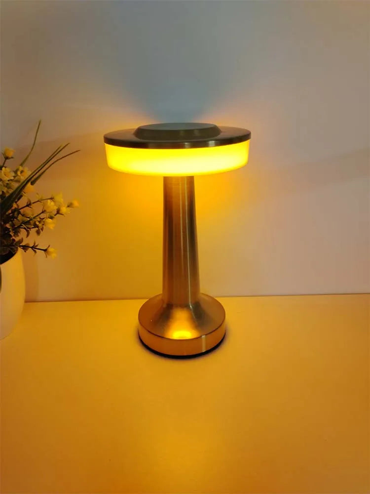 Gold cordless LED table lamp with wide domed shade, warm light emitting from center