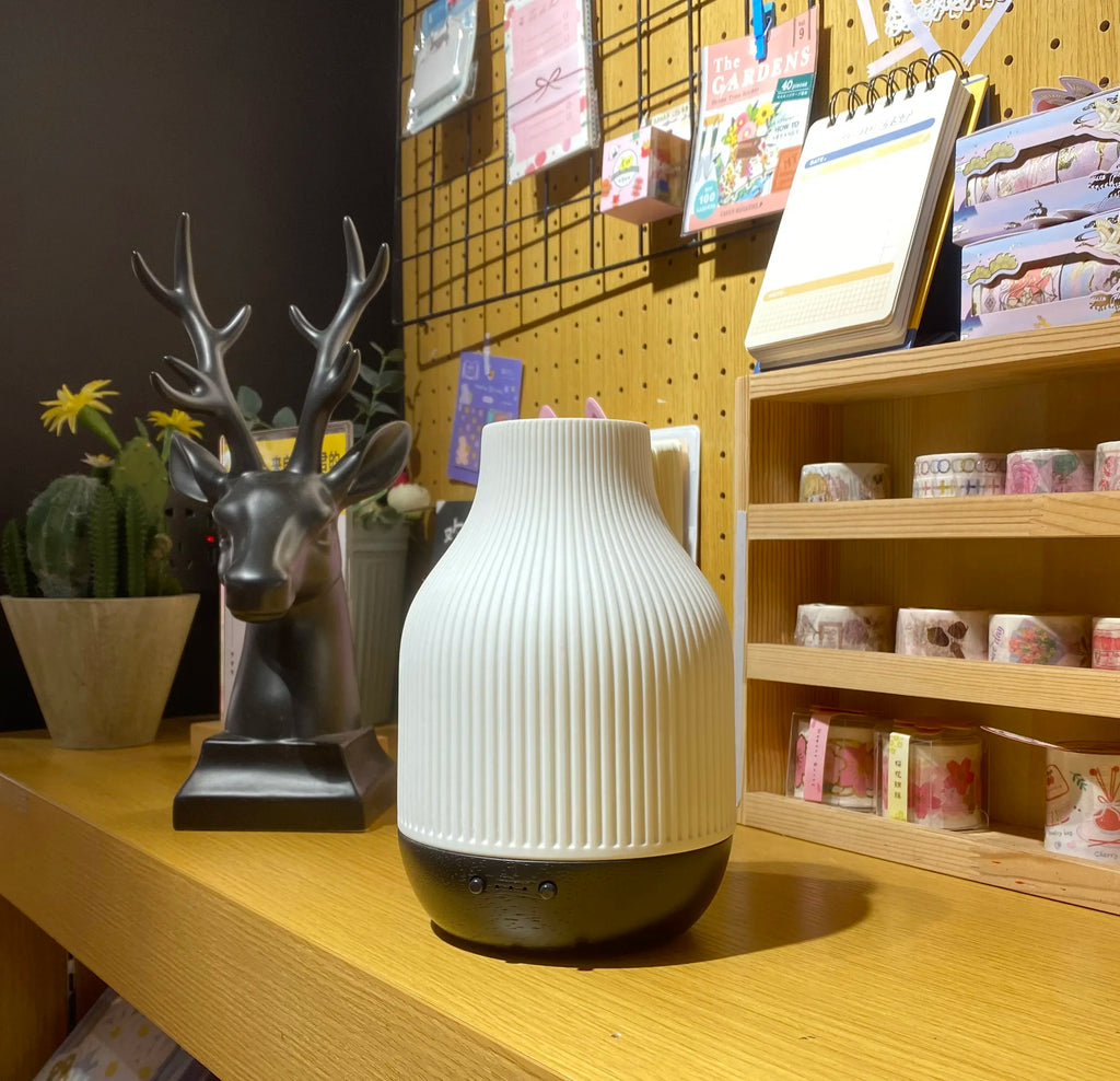 White ceramic aroma diffuser with ribbed body and wood-effect bottom, front control holes