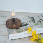 Clear LED bulb night lamp resting on round dark wooden base