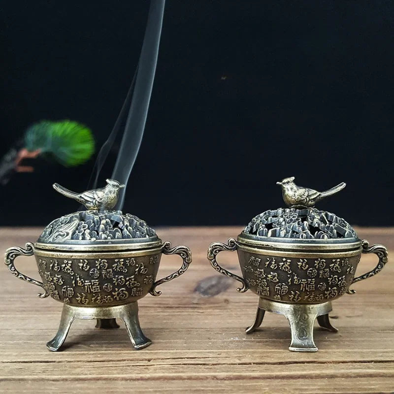 Two copper lotus incense burners with bird-topped lids and long incense sticks