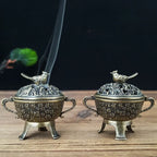 Two copper lotus incense burners with bird-topped lids and long incense sticks