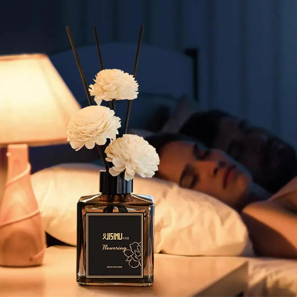 Mini reed diffuser bottle with black reeds and white flowers on bedside table, 50ml
