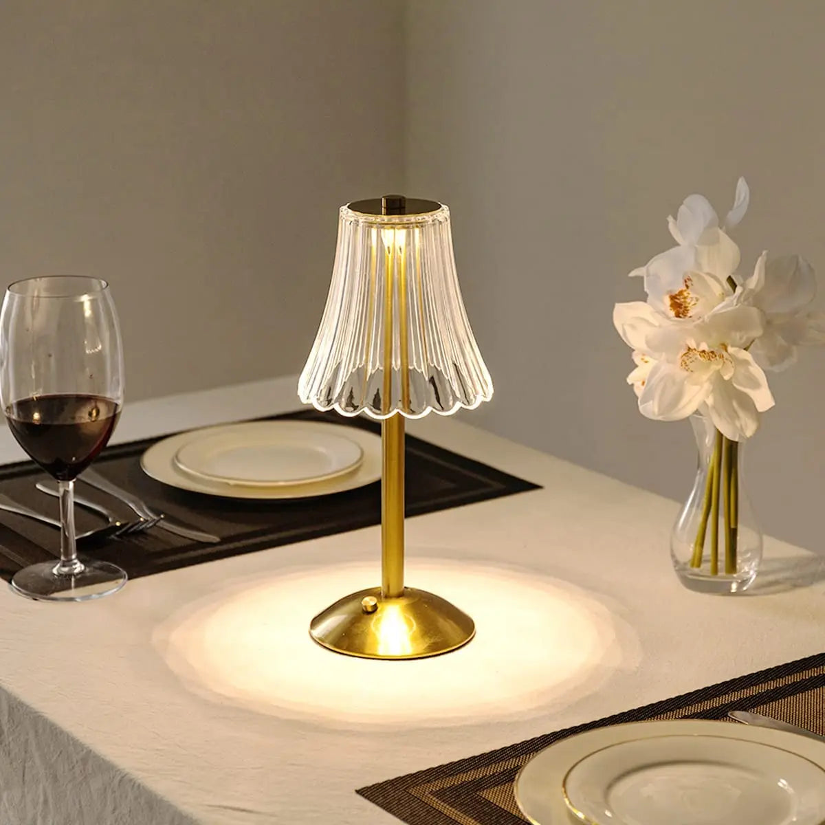 Cordless table lamp with pleated glass shade and gold base on bedside tabletop