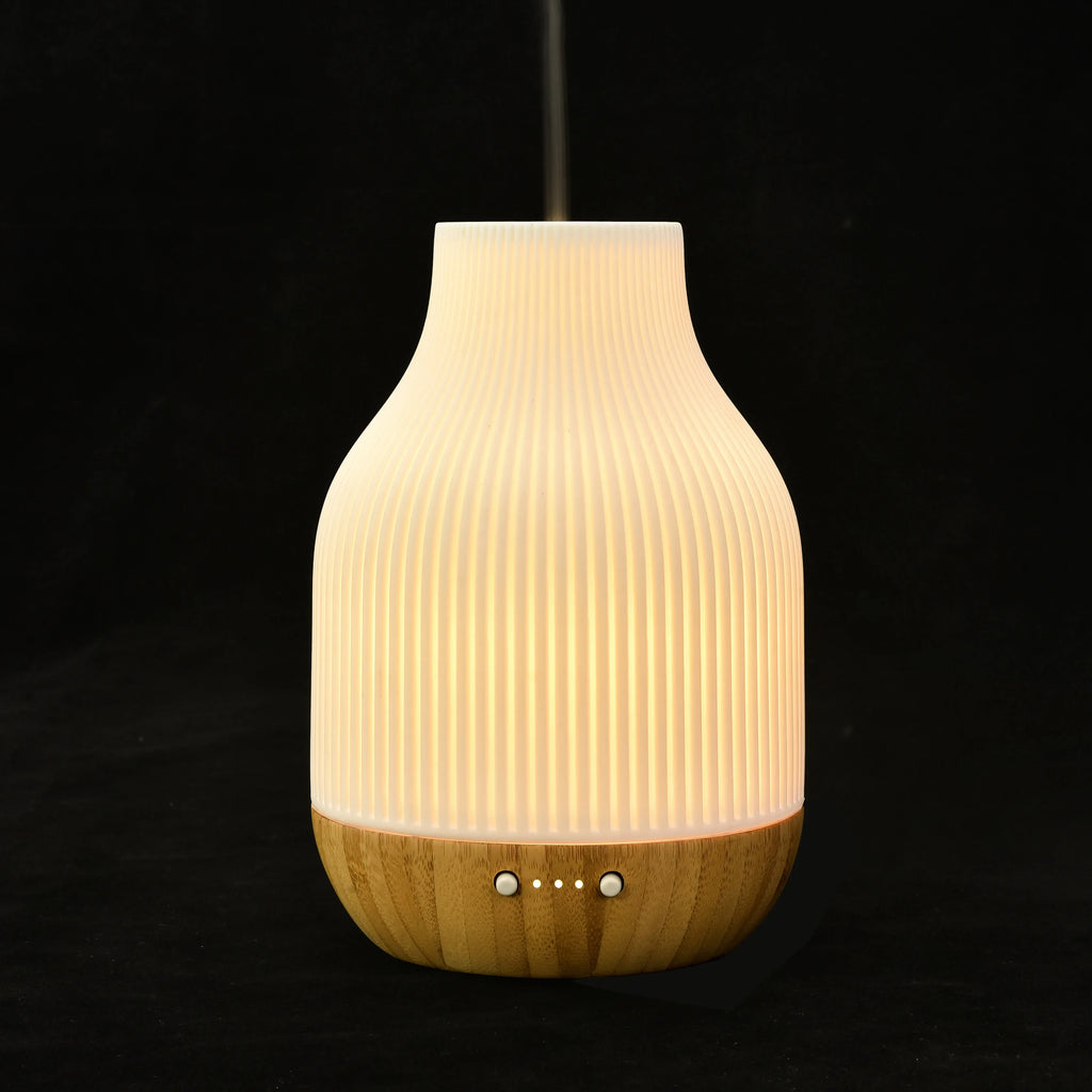 Ceramic aroma diffuser with white ribbed top and light wood base, control holes on front
