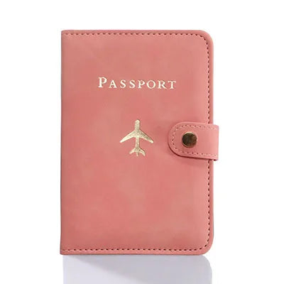 Petal pink passport folio with “PASSPORT” text and airplane emblem, snap strap closure