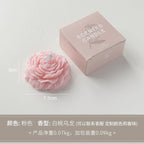 Peony sculptural candle, pale pink flower with wick beside branded gift box, size shown