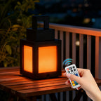 Black pixel lantern night light on outdoor table with warm orange glow and remote control