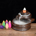 Backflow incense burner with small cones around it, including pink and green cones