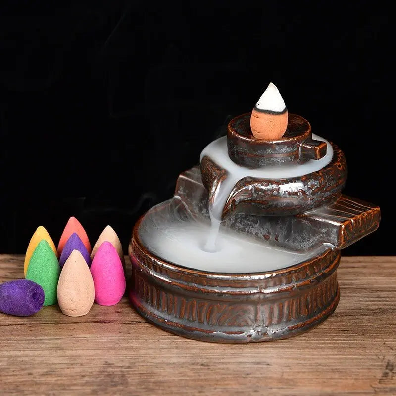 Backflow incense burner with small cones around it, including pink and green cones