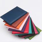 Blue passport sleeve stacked over other colors, embossed “PASSPORT” on the front