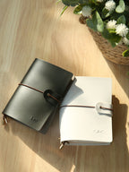 Midnight black vegan leather passport holder with wrap strap, buckle, and engraved name