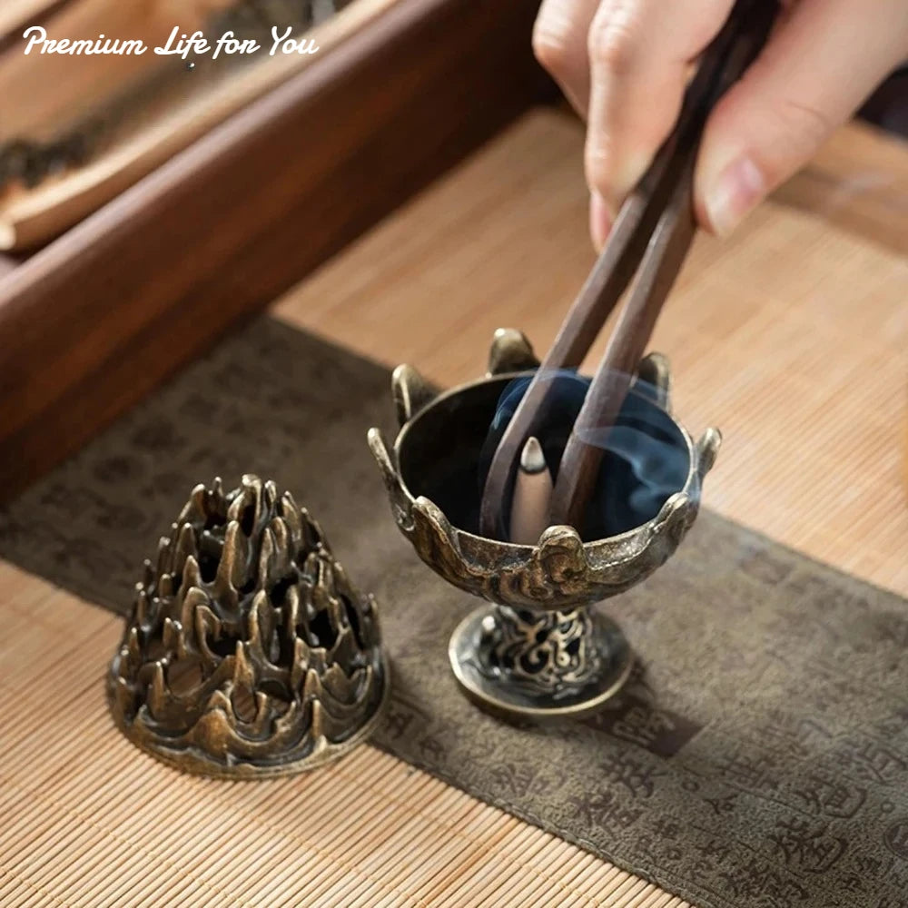 Copper-toned incense censer on a tray with carved flame-lotus top; incense smoke rising.