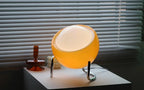 Amber glass globe lamp with warm internal light and chrome curved supports