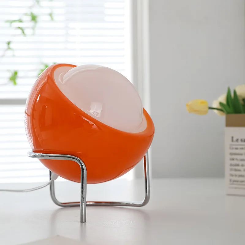 Orange glass globe lamp on chrome base stand, oval diffuser glowing amber
