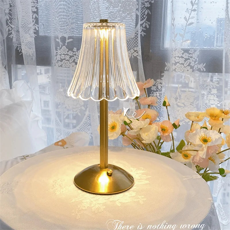 Cordless table lamp with pleated glass shade and gold base on white tablecloth