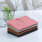 Stack of blush pink, slate grey, cognac brown, and black passport covers with airplane icons