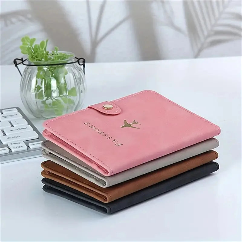 Stack of blush pink, slate grey, cognac brown, and black passport covers with airplane icons