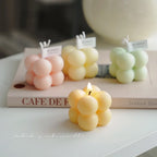 Scented bubble candle cluster in warm yellow, with flame on a flat surface