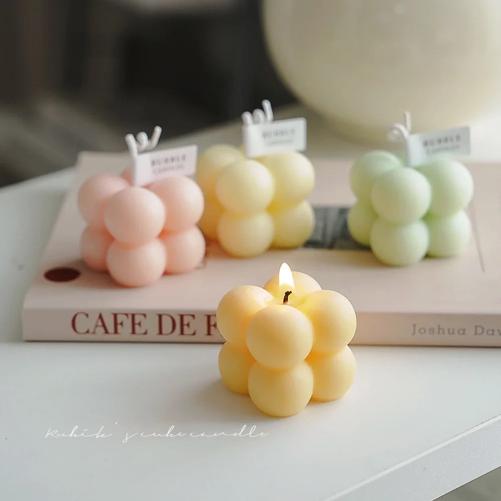 Scented bubble candle cluster in warm yellow, with flame on a flat surface