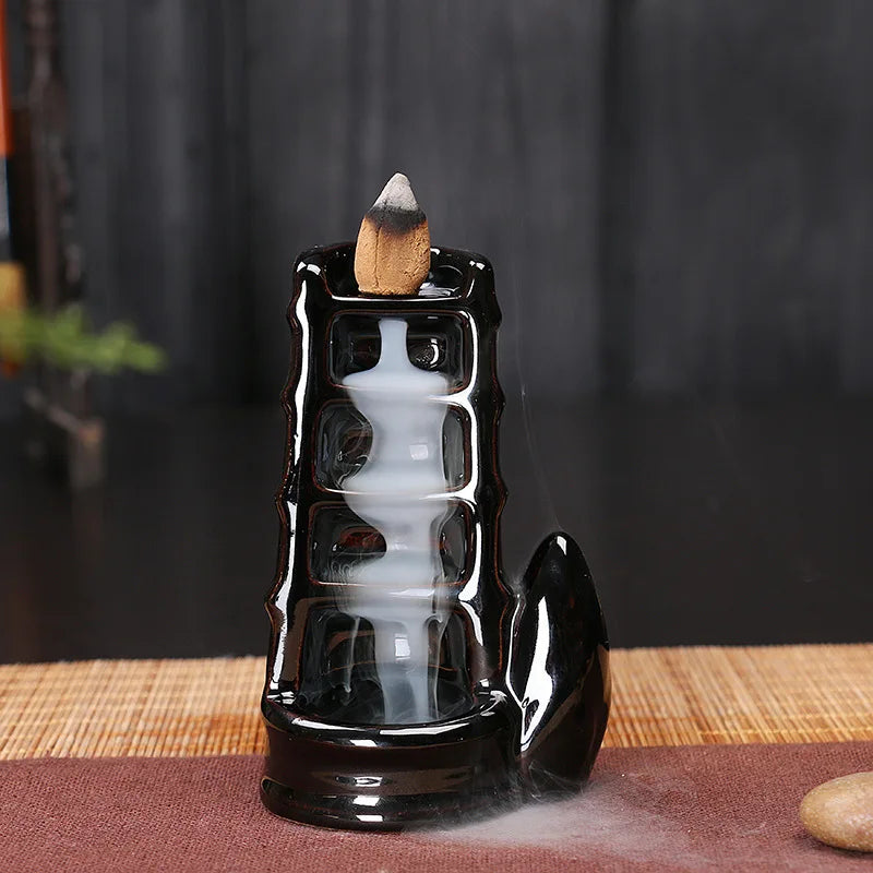 Black glossy backflow incense tower burner with cone incense on top and smoke