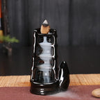 Black glossy backflow incense tower burner with cone incense on top and smoke