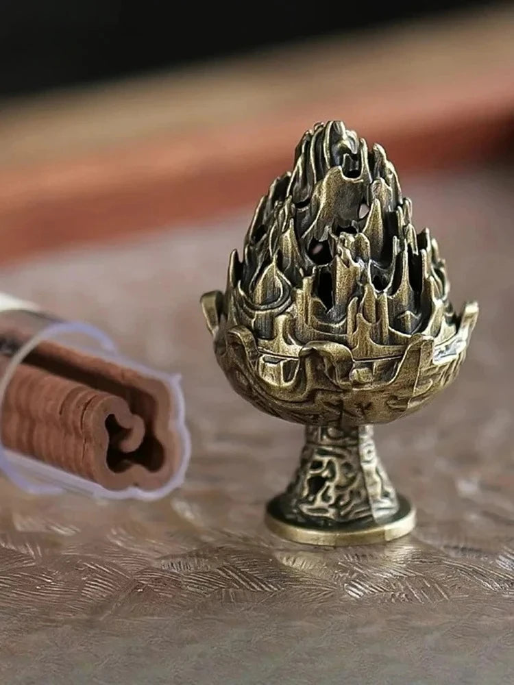 Copper incense censer with flame-top bowl beside burning incense stick and smoke