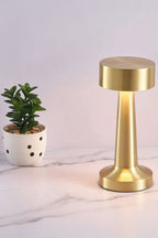 Gold cordless LED table lamp with wide top shade and glowing light pillar base