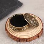 Round engraved incense burner with lid open on a wooden base