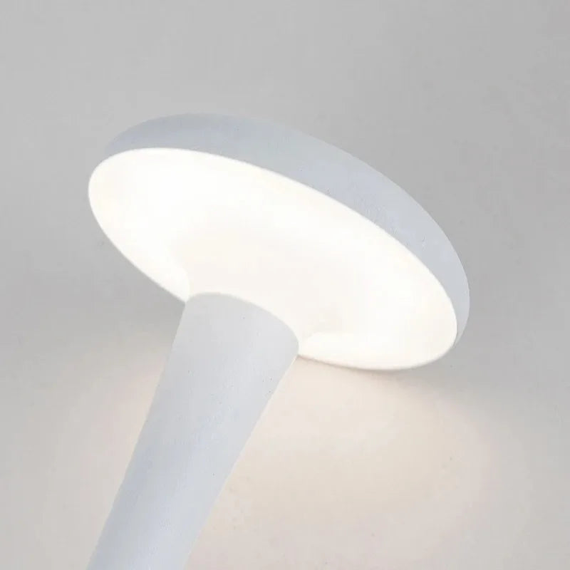 Pearl white cordless mushroom touch table lamp head glowing with soft, warm light.