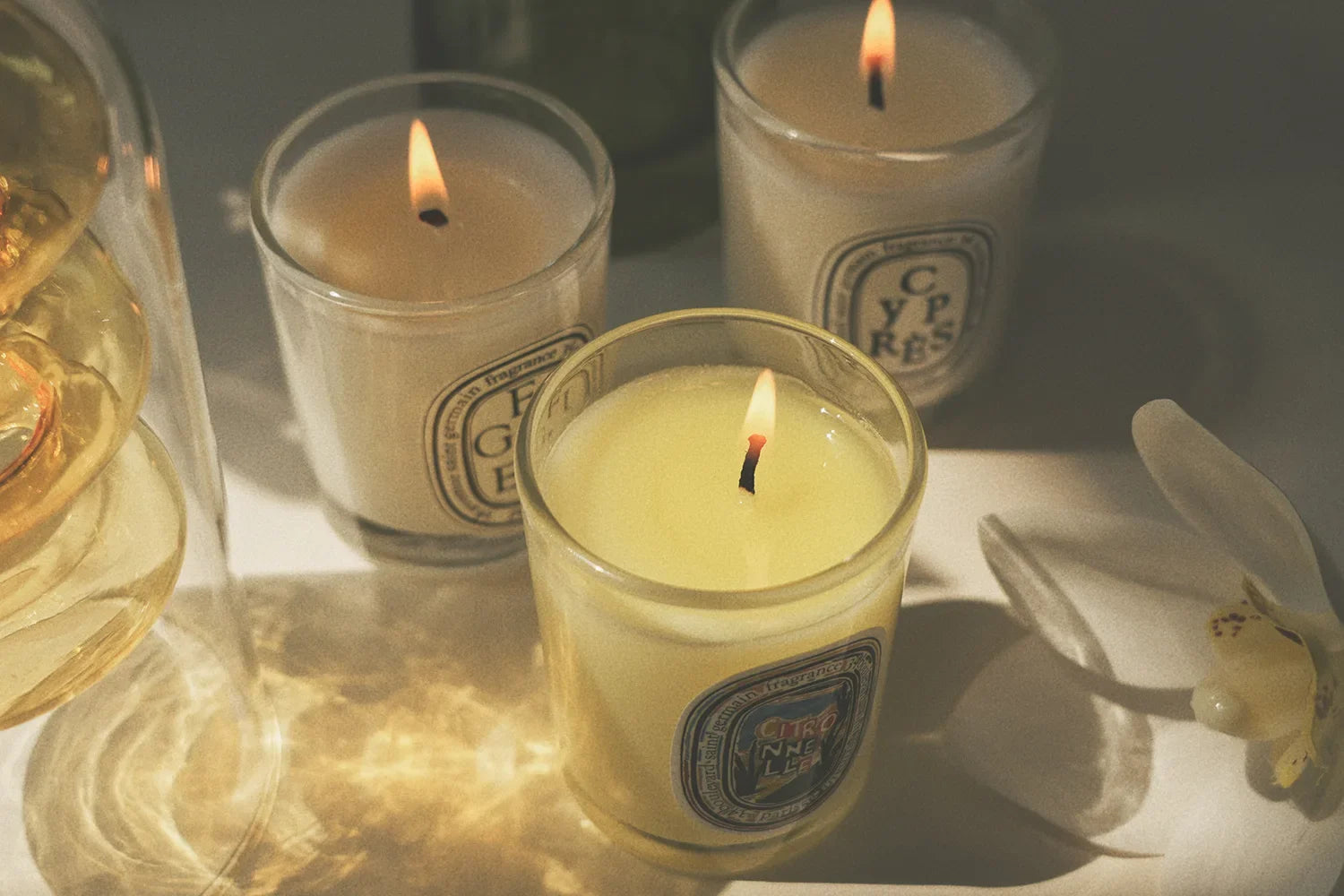 Gros plan sur bougie parfumée 190 g en verre, flamme allumée, plusieurs verres.