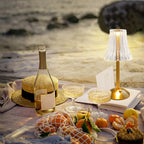 Cordless table lamp with ribbed clear shade and gold base, warm glow switched on