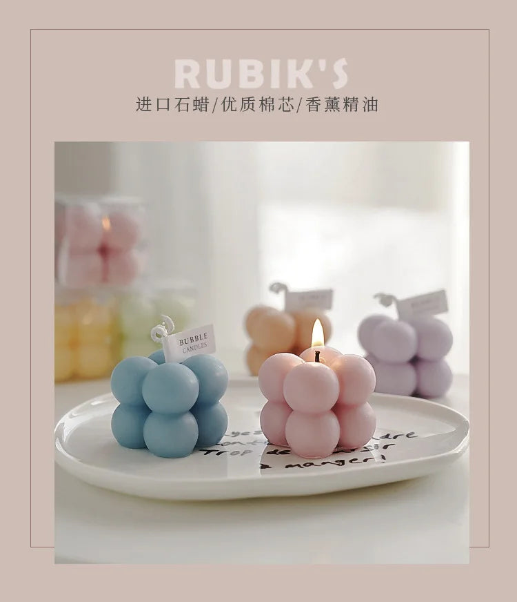 Sculptural bubble candles, blue and pink tones, each with a lit wick