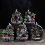 Resin landscape waterfall incense burner with green trees and orange-roof houses, purple incense cone