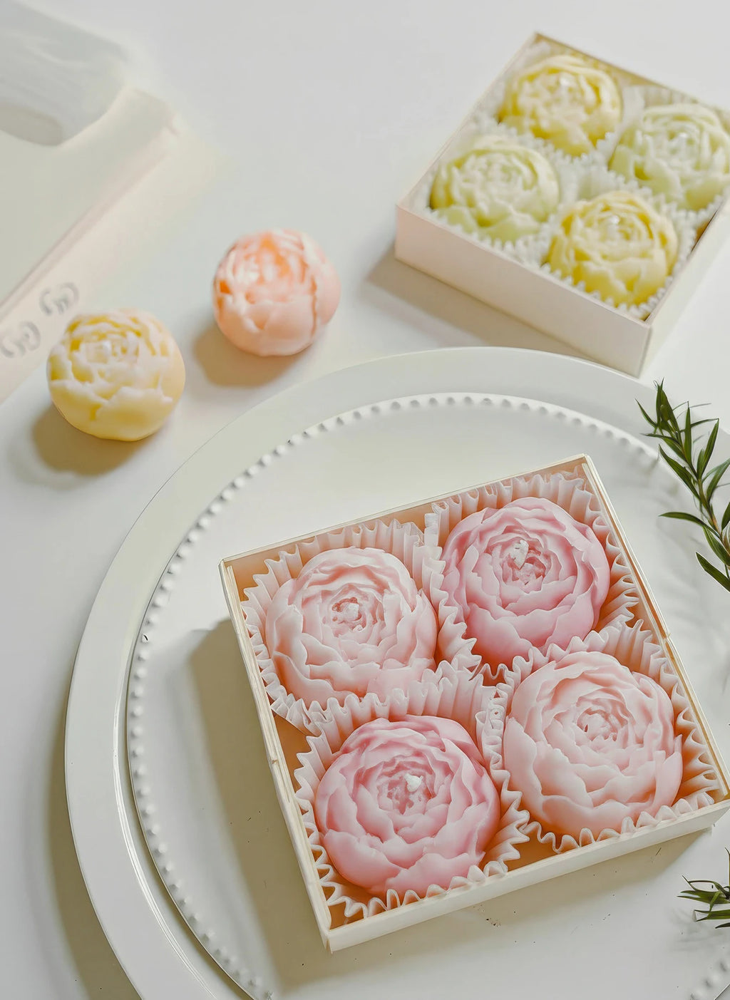 Round tray with pastel rose-shaped soy wax candles and a yellow candle box