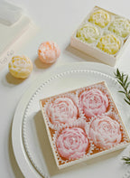 Round tray with pastel rose-shaped soy wax candles and a yellow candle box
