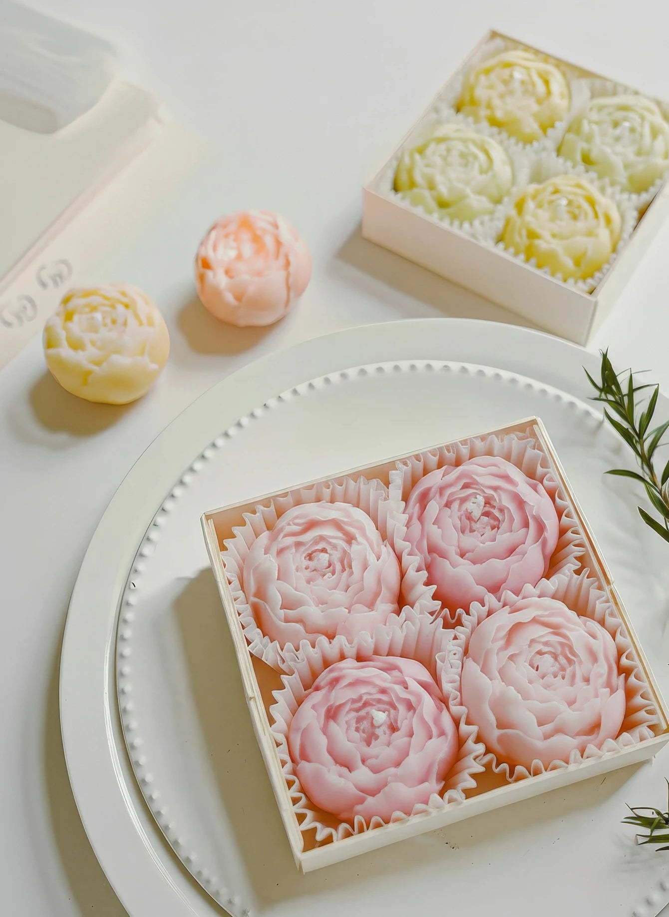 Round tray with pastel rose-shaped soy wax candles and a yellow candle box