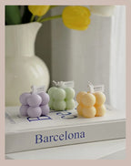 Three pastel bubble candle clusters in purple, green, and yellow on display blocks