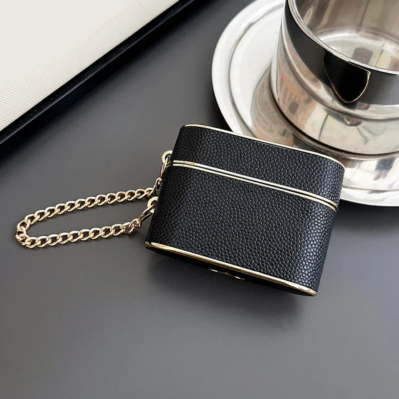 Obsidian (dark) wrist strap AirPods case with gold chain and gold trim.