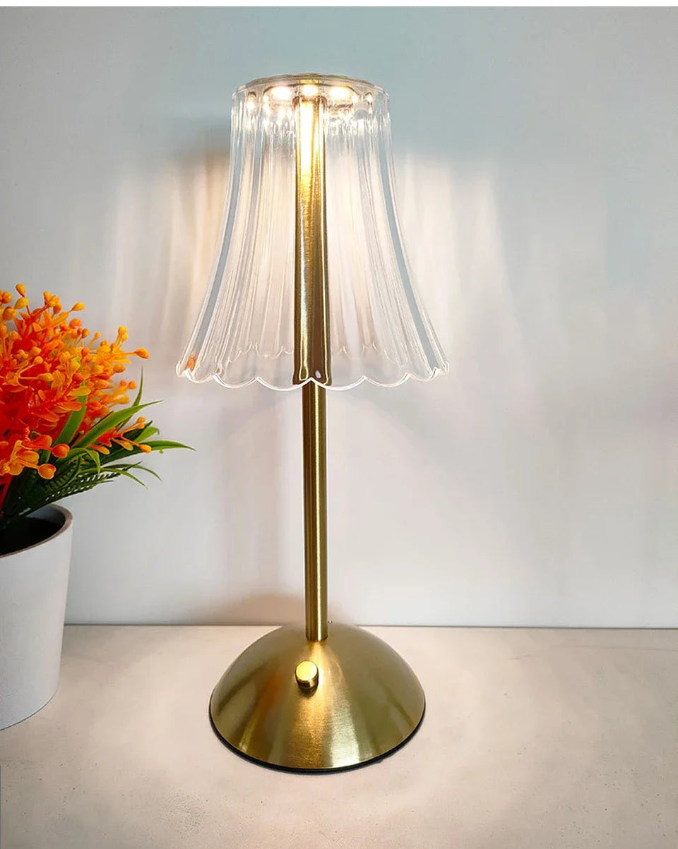 Cordless dimmable night lamp lit up, ribbed clear shade on gold stem and base
