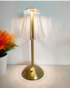 Cordless dimmable night lamp lit up, ribbed clear shade on gold stem and base
