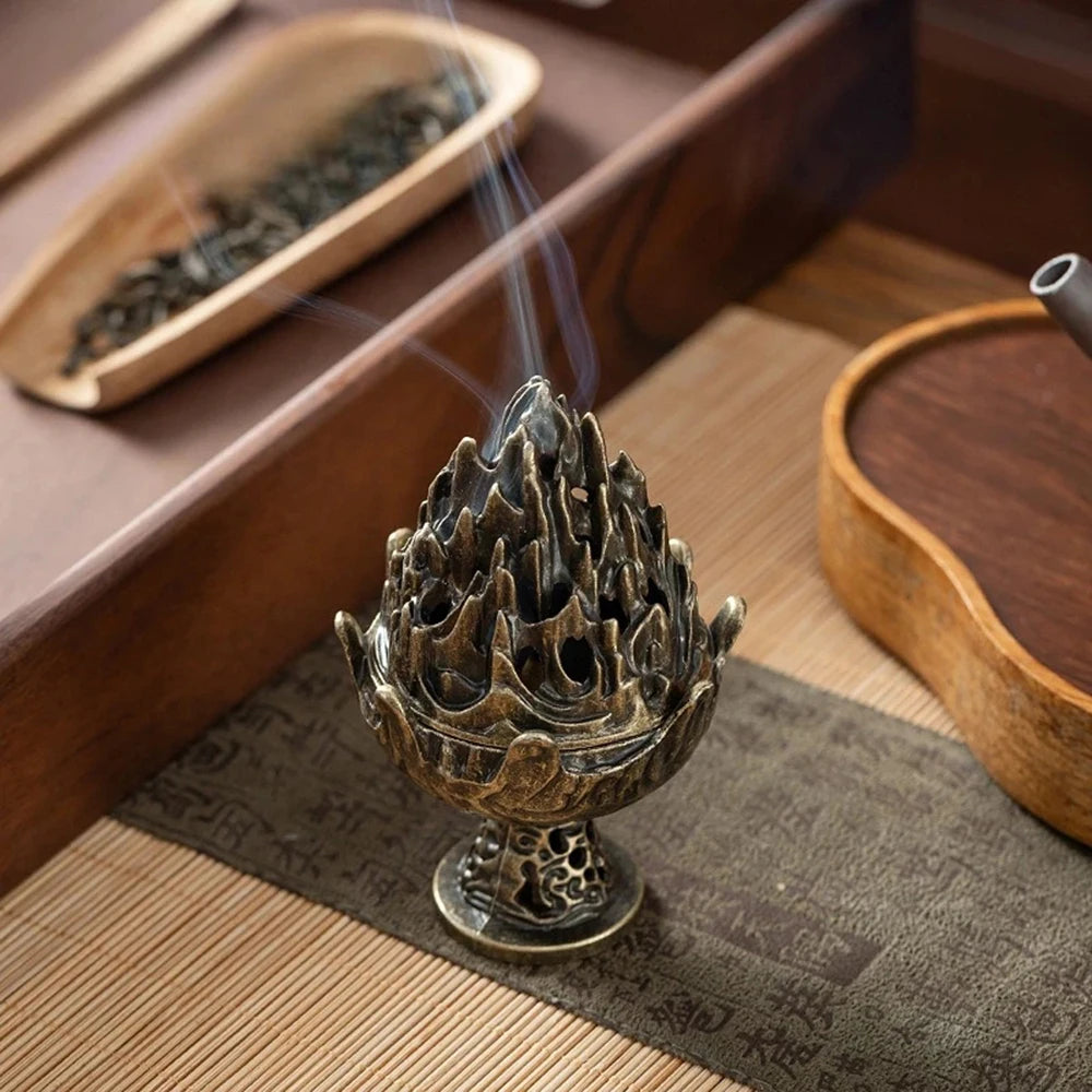 Copper-toned incense censer with ornate flame-lotus top on a stand; incense smoke rising.