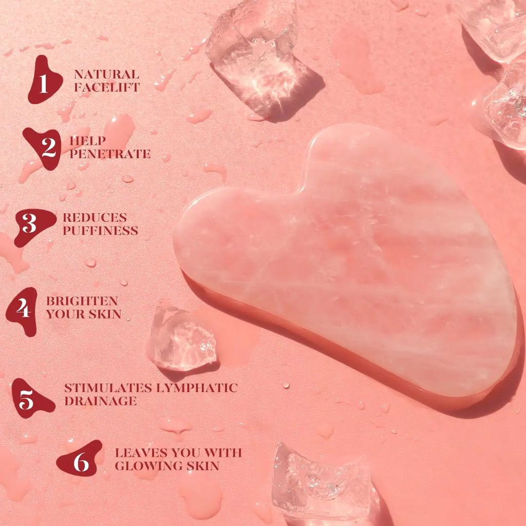 Pink gua sha heart tool and small roller pieces on textured surface