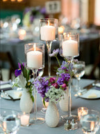 Trio of clear glass candle holders with lit candles in stemmed goblet cups