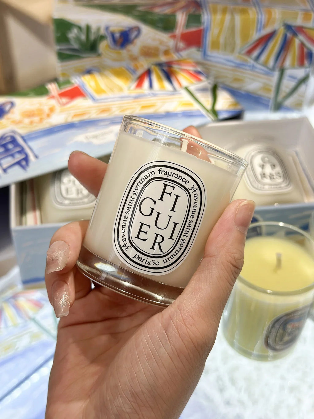 Bougie figuier 190 g : pot en verre transparent avec mèche, tenue à la main.
