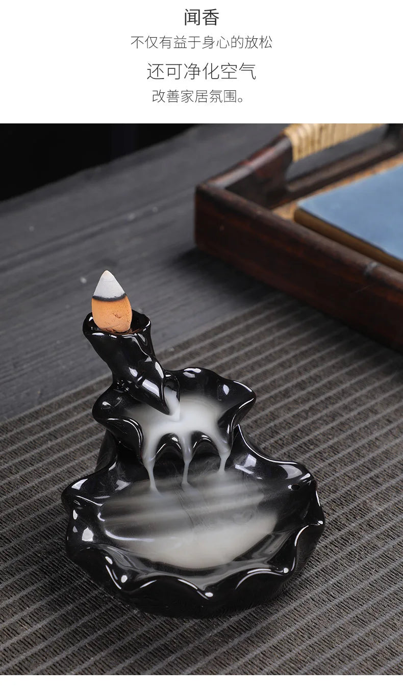Tower backflow incense burner with white cone tip and swirling smoke pool in black tray