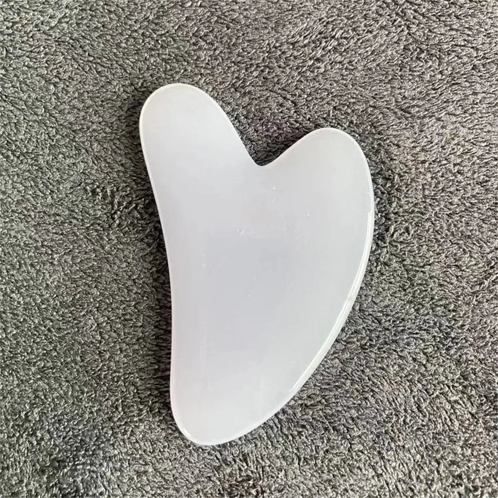 White jade gua sha stone with curved teardrop shape and rounded edges.