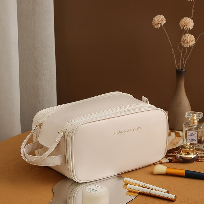 White structured travel vanity case with zip closure, crossbody strap, and front monogram