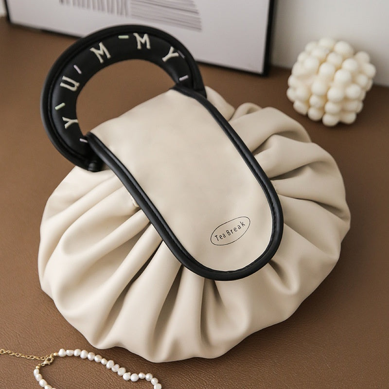 Cream drawstring wash bag with black oval loop handle and Tea Break patch